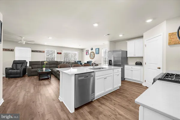 a kitchen with stove a sink dishwasher and white cabinets with wooden floor