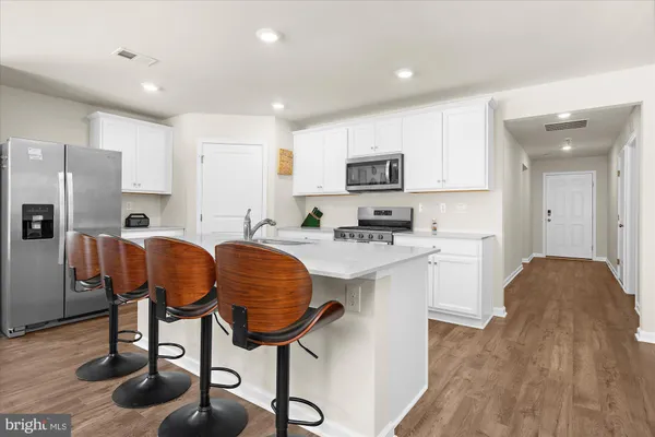a kitchen with stainless steel appliances granite countertop a table chairs refrigerator and microwave