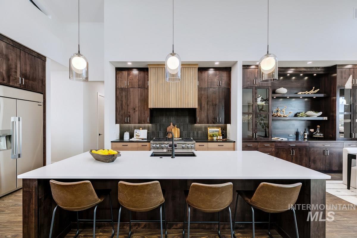 525 Founder Avenue Middleton, ID 83644 - Photo 18 of 50 Dual tone kitchen with dark wood-style flooring, stainless steel built in fridge, a kitchen bar, a large island with sink, and a high ceiling