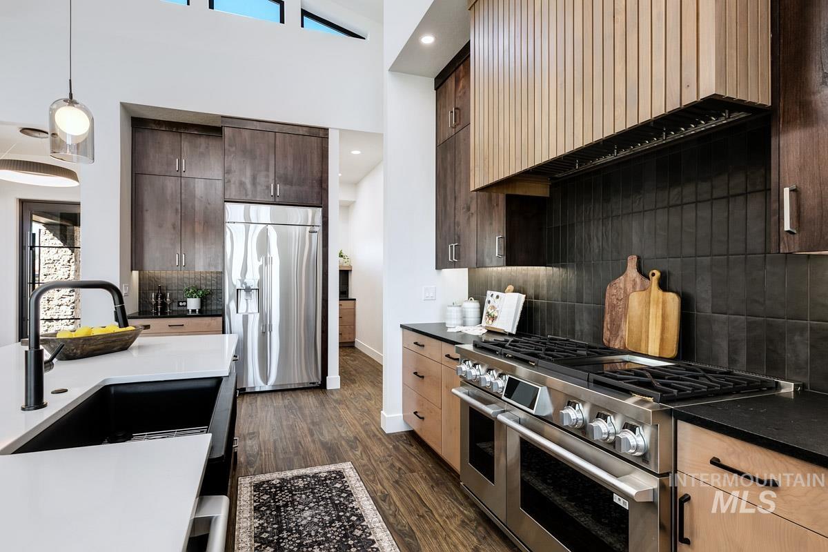 525 Founder Avenue Middleton, ID 83644 - Photo 20 of 50 Kitchen featuring premium appliances, dark wood finished floors, dark wood finish cabinetry, a high ceiling, and hanging light fixtures