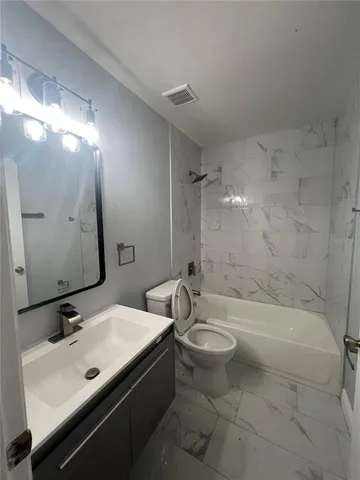 a bathroom with a bathtub shower sink mirror and toilet