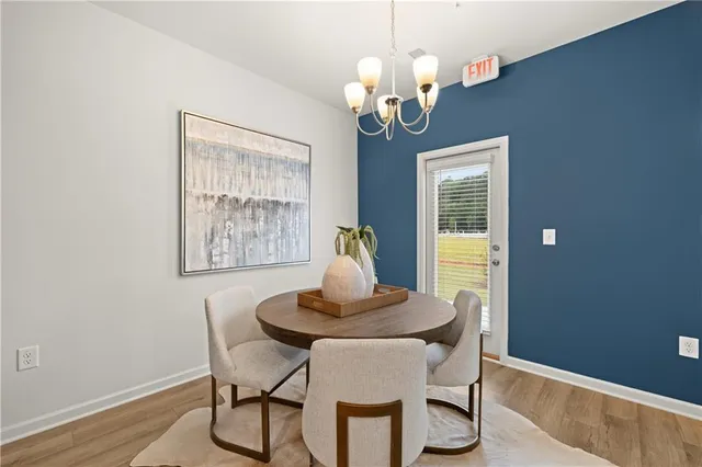 a dining room with chandelier and wooden floor