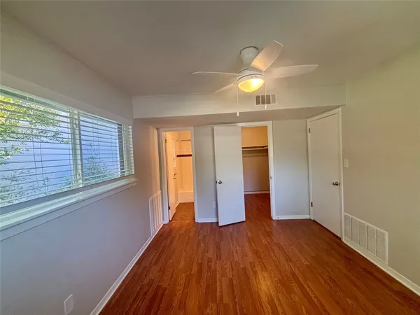 a view of empty room with wooden floor and fan