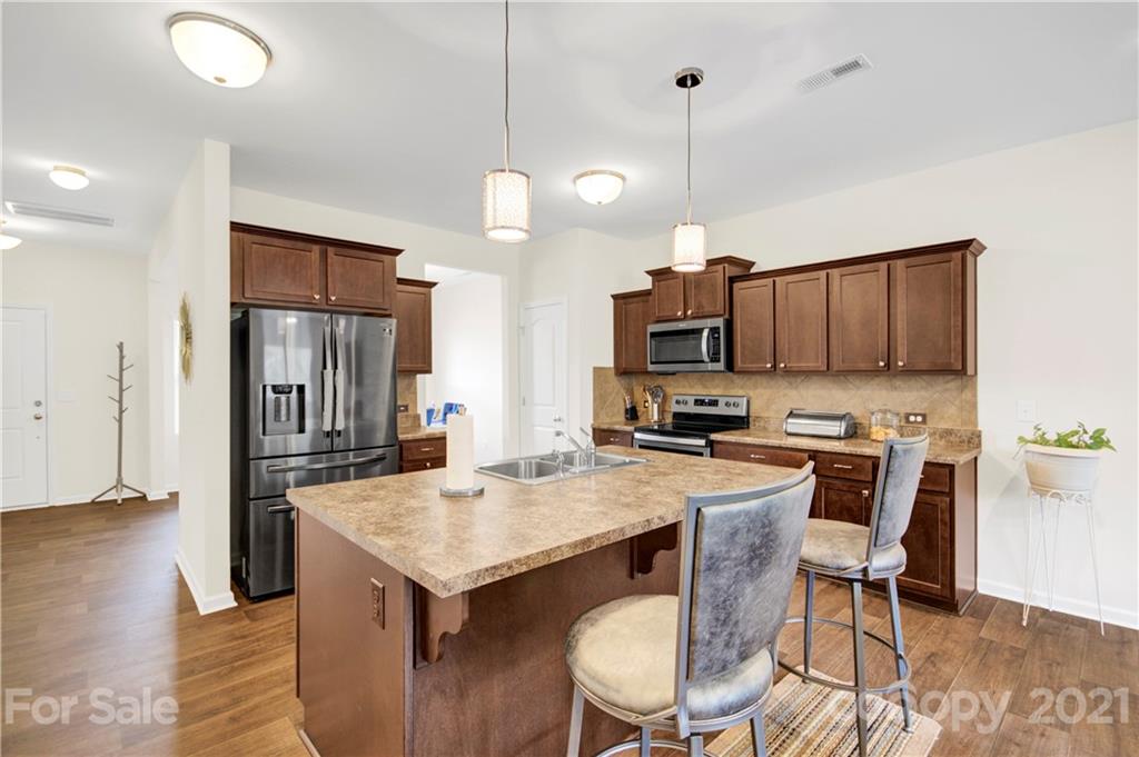 9026 Colwick Hill Road Charlotte, NC 28215 - Photo 7 of 21 a kitchen with a stove a refrigerator and a dining table with wooden floor