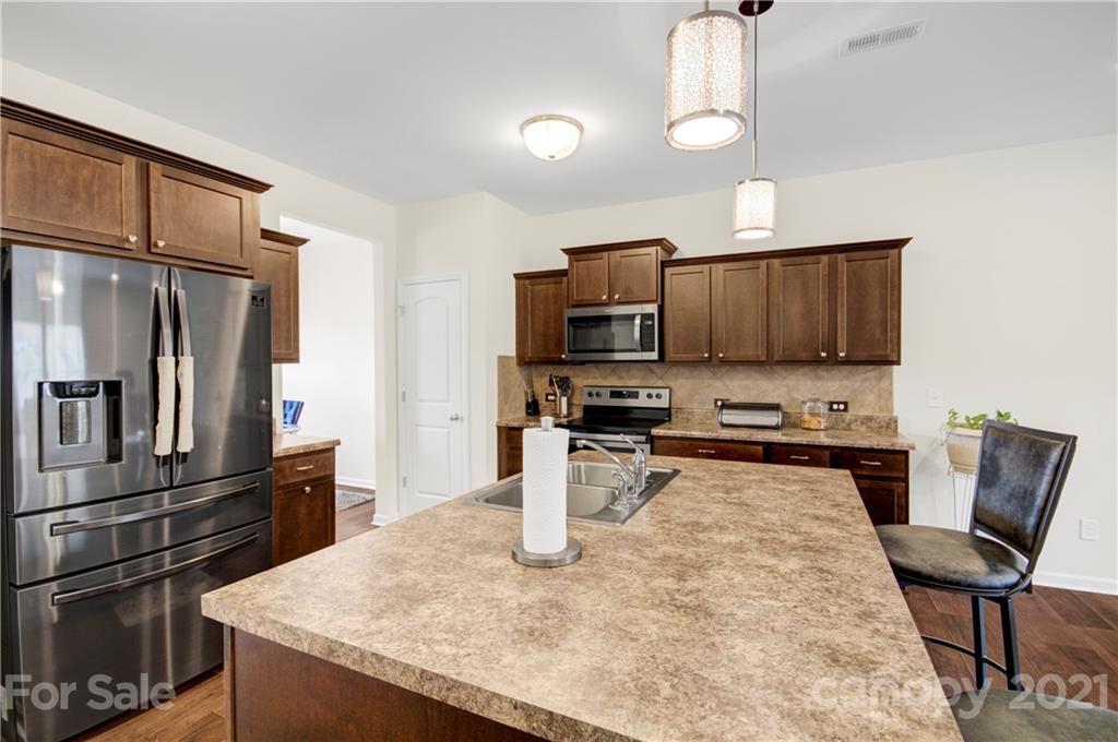 9026 Colwick Hill Road Charlotte, NC 28215 - Photo 8 of 21 a kitchen with stainless steel appliances granite countertop a sink a stove a refrigerator cabinets and chairs
