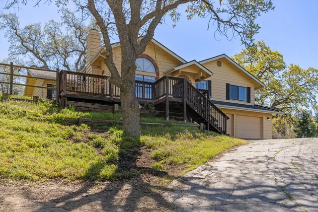 a backyard of a house with large trees and wooden fence