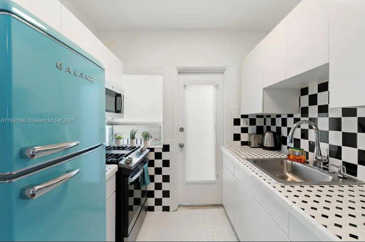 7721 Harding Avenue, Unit 4 Miami Beach, FL 33141 - Photo 5 of 16 a kitchen with a sink a stove and chairs