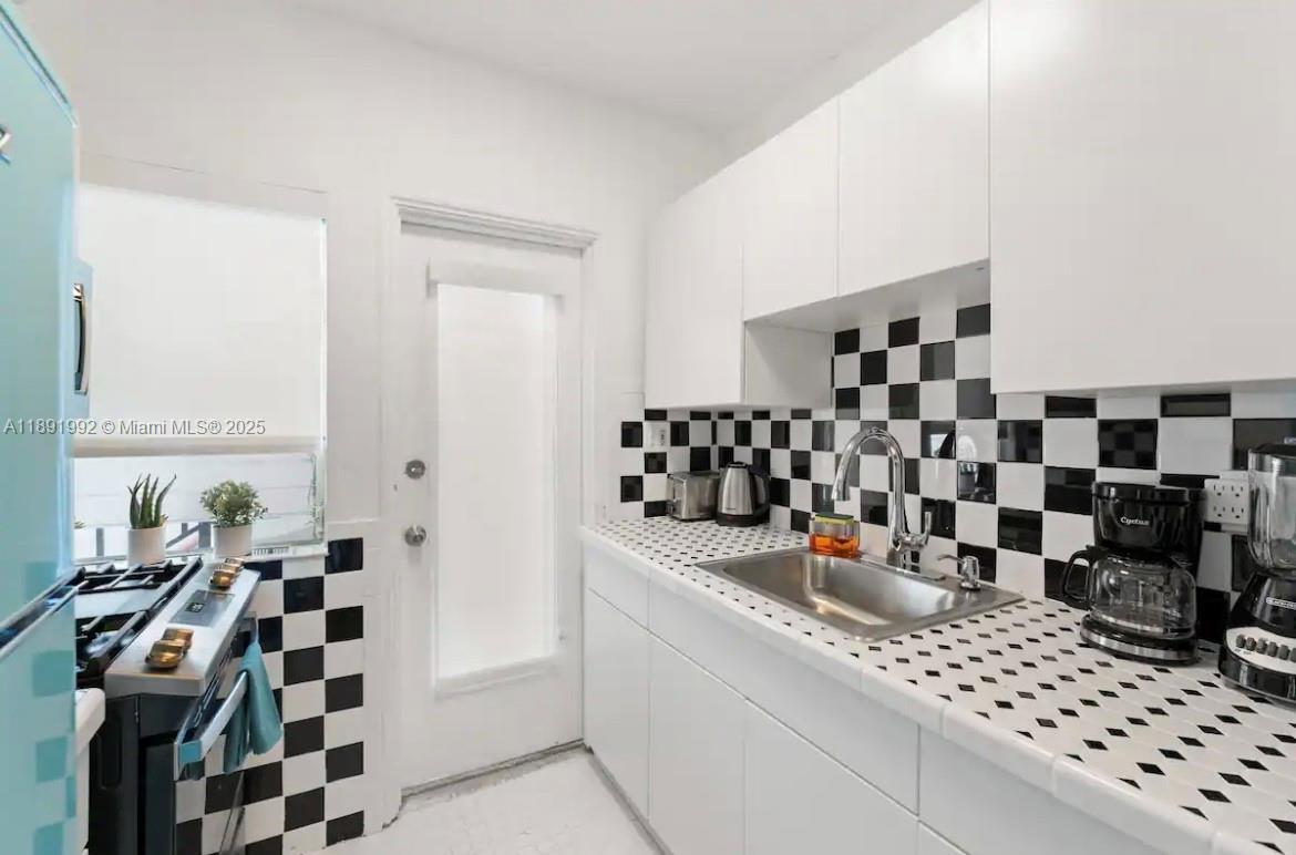 7721 Harding Avenue, Unit 4 Miami Beach, FL 33141 - Photo 6 of 16 a kitchen with a checkered floor and white cabinets
