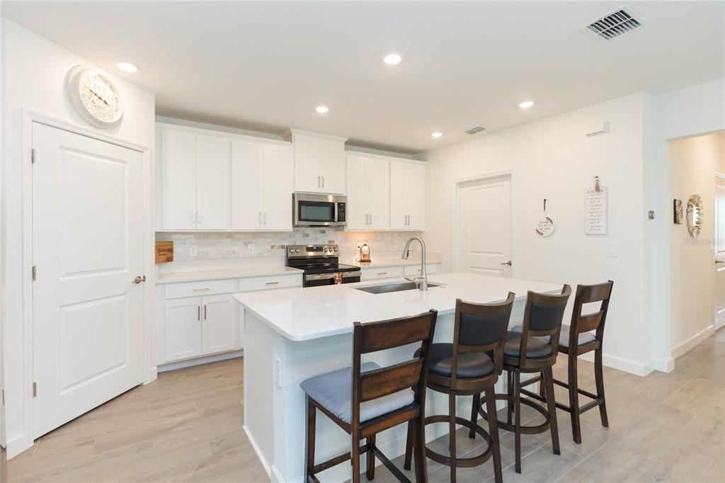 10806 Gable Dig Loop San Antonio, FL 33576 - Photo 18 of 73 a kitchen with kitchen island granite countertop a sink a stove a refrigerator and island with chair