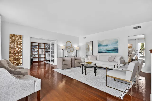 a bedroom with a bed a couch and a dresser with wooden floor