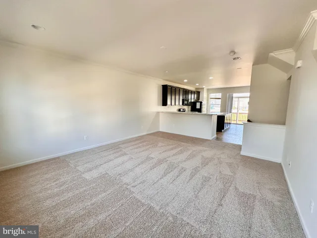 a view of empty room with kitchen and window
