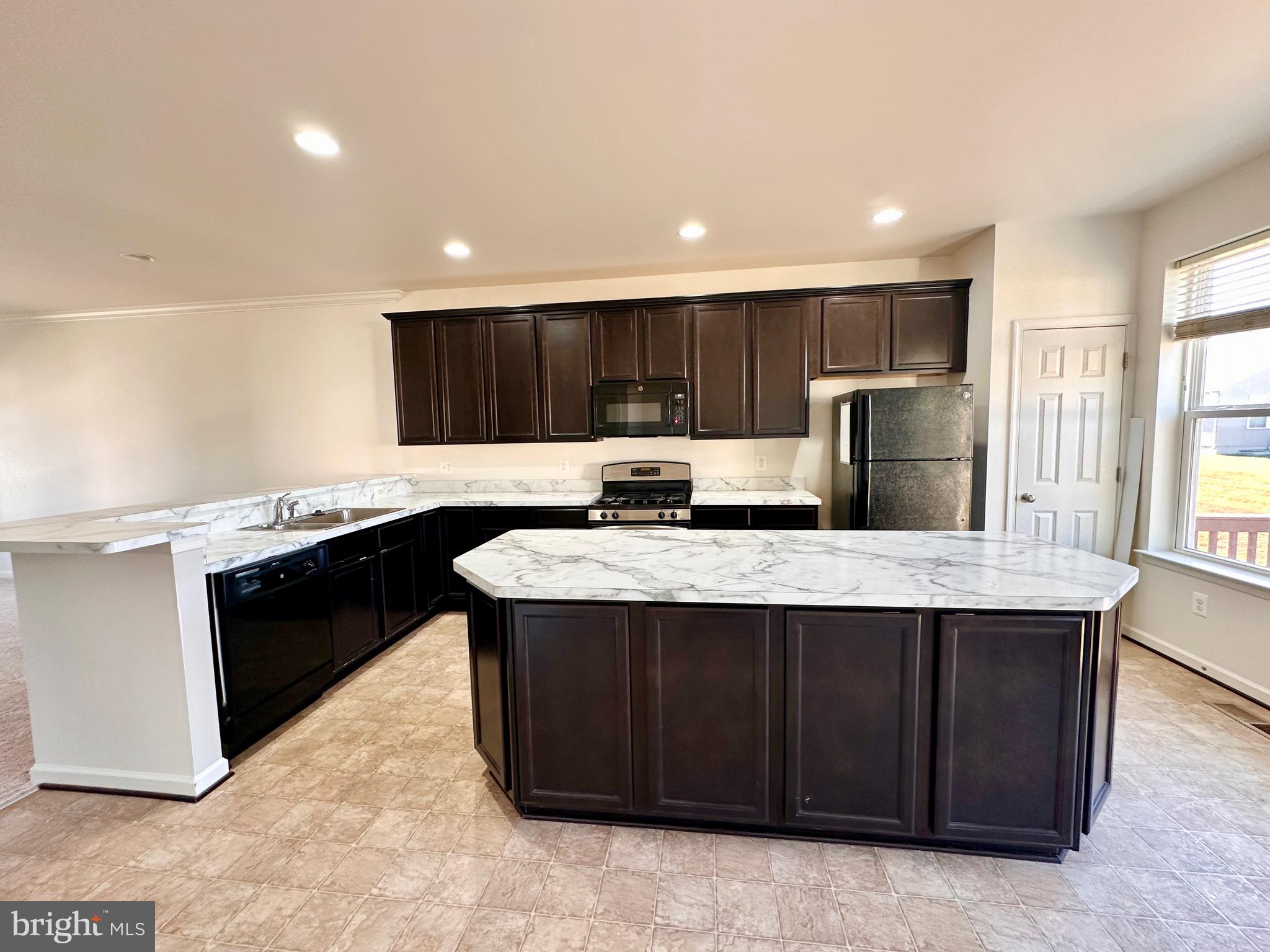 111 Fading Star Court Stephenson, VA 22656 - Photo 8 of 25 a kitchen with kitchen island granite countertop wooden cabinets a refrigerator and a sink