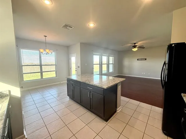 a kitchen with granite countertop a refrigerator and a stove top oven