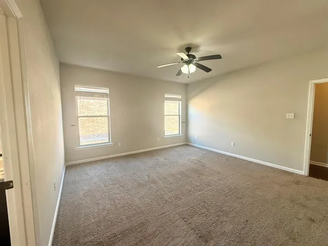 an empty room with windows and ceiling fan