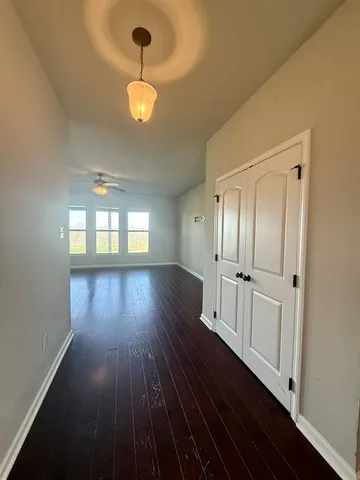 a view of empty room with wooden floor and fan