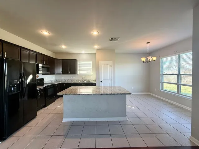 a large kitchen with granite countertop a large counter top stainless steel appliances and cabinets