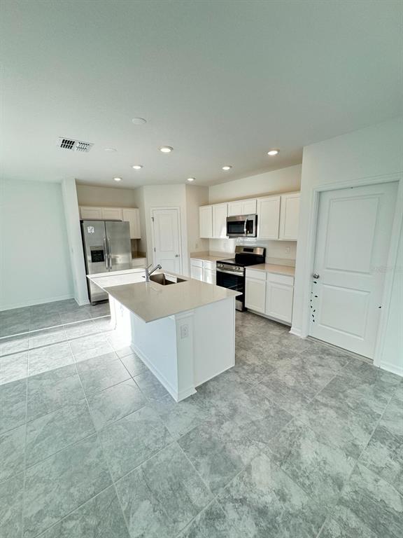 724 Reggie Road Winter Haven, FL 33859 - Photo 7 of 26 a large white kitchen with kitchen island a sink a stove and a refrigerator