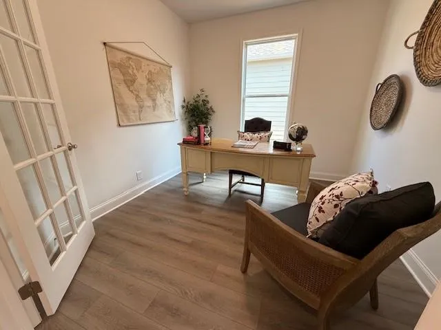 a view of an empty room with wooden floor fireplace and a window