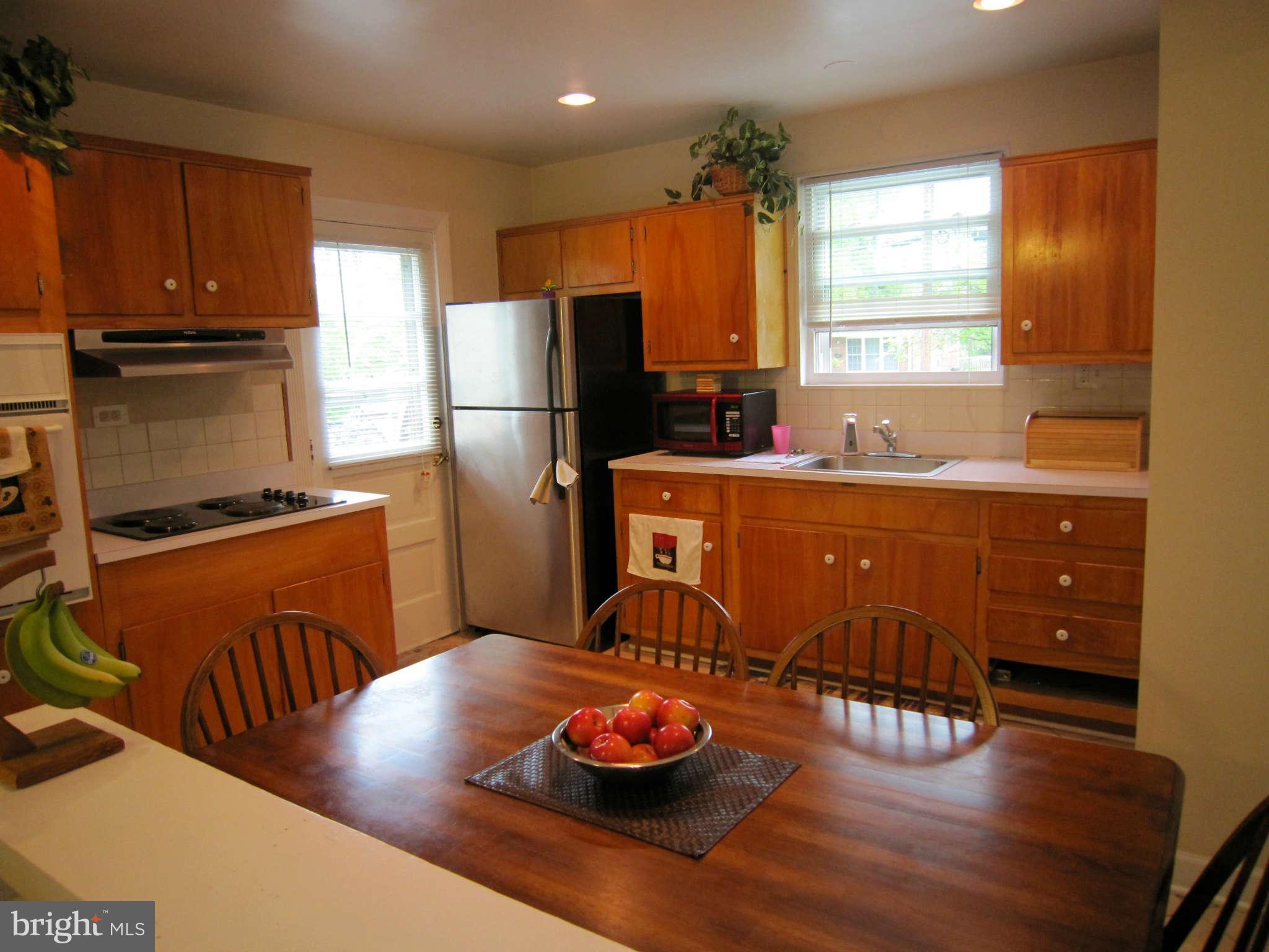 4310 Emden Street Silver Spring, MD 20906 - Photo 3 of 21 a kitchen with stainless steel appliances granite countertop a refrigerator a sink dishwasher a stove a dining table and chairs with wooden floor