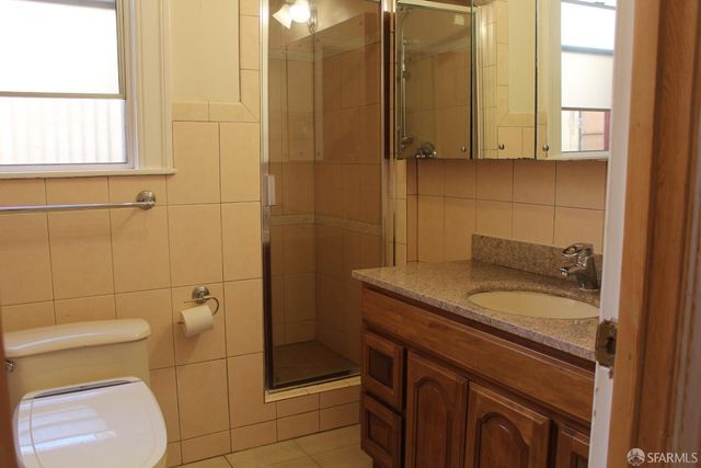a bathroom with a granite countertop sink a toilet and shower