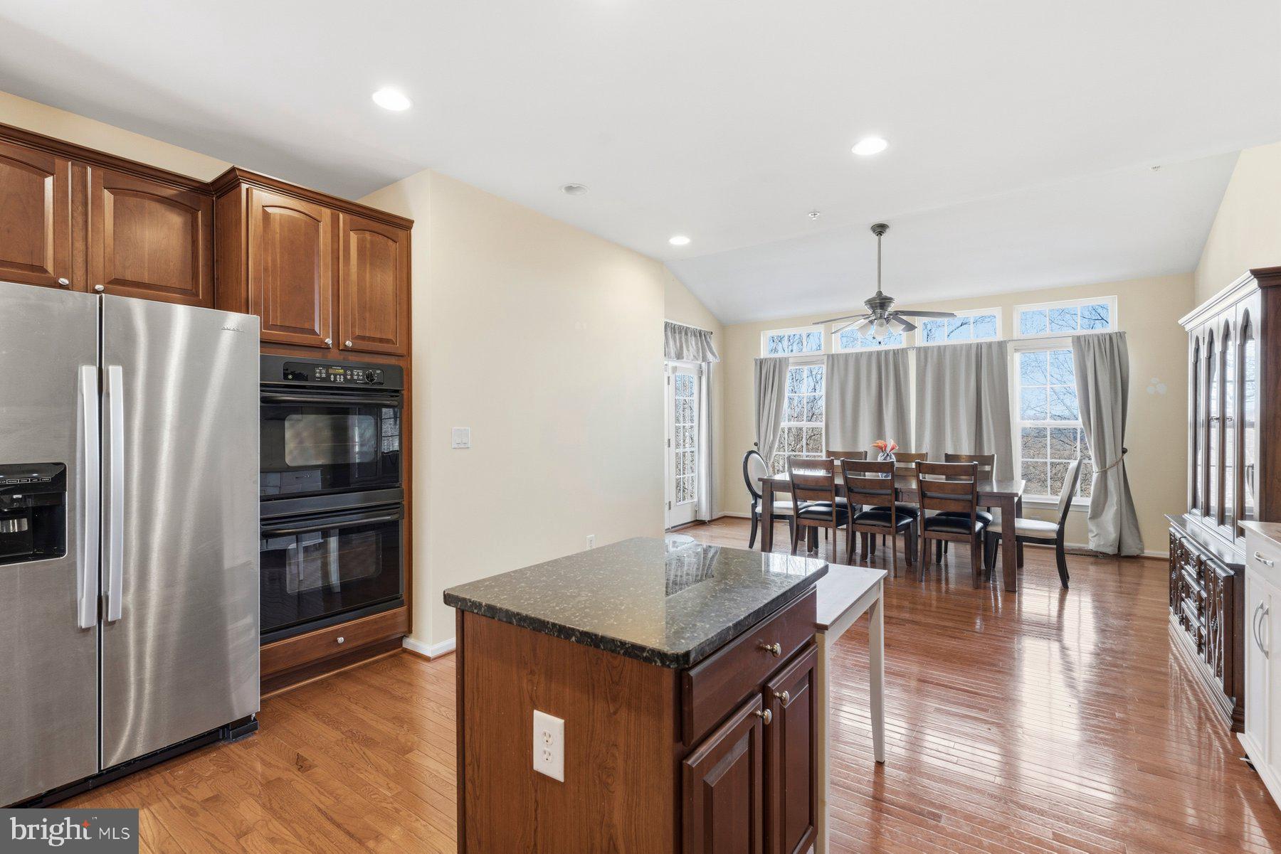 8330 Meadowsweet Road, Unit 8330 Pikesville, MD 21208 - Photo 10 of 55 a kitchen with stainless steel appliances granite countertop a refrigerator a stove and a dining table with wooden floor