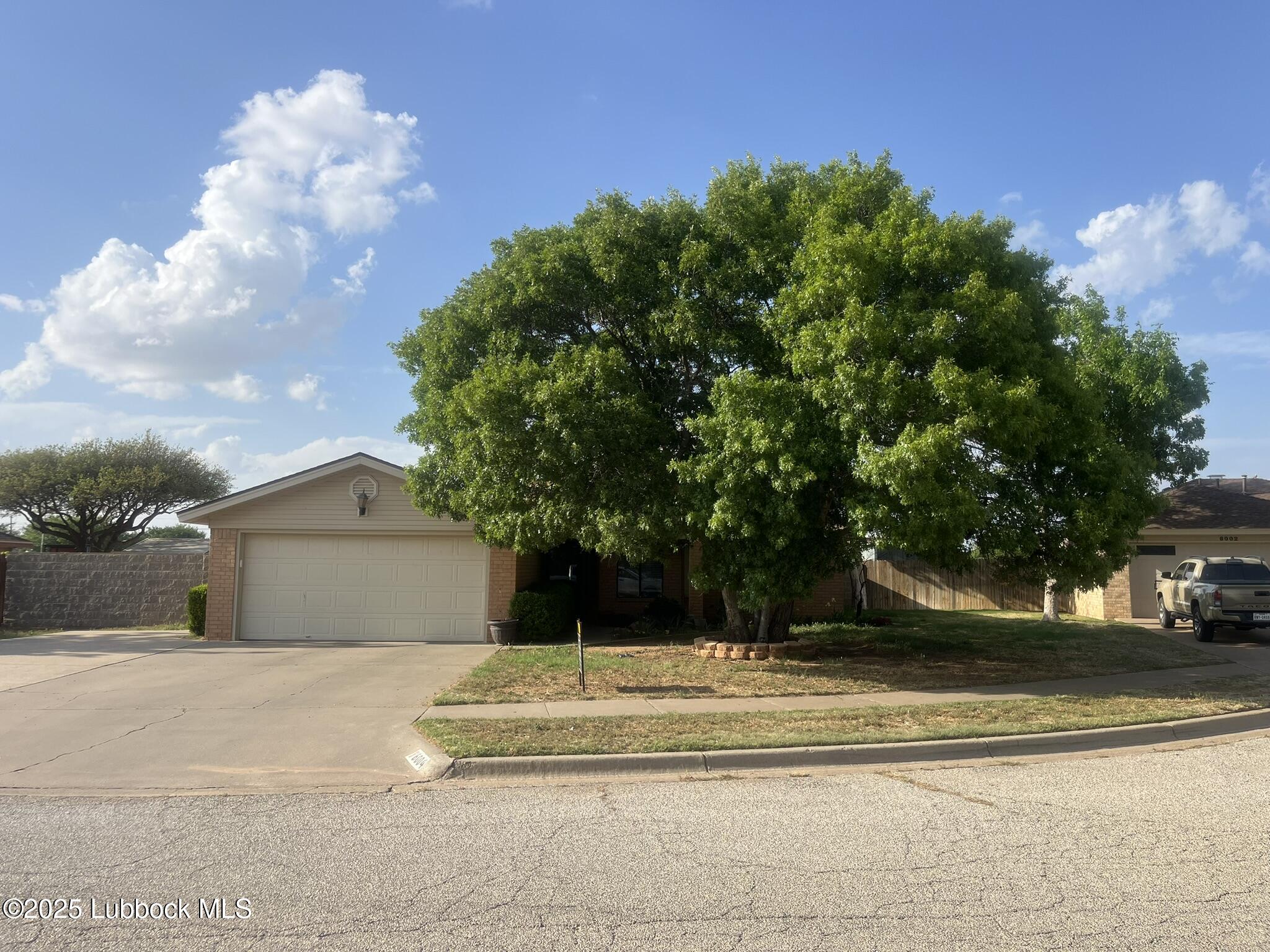 a view of a house with a yard and a large tree