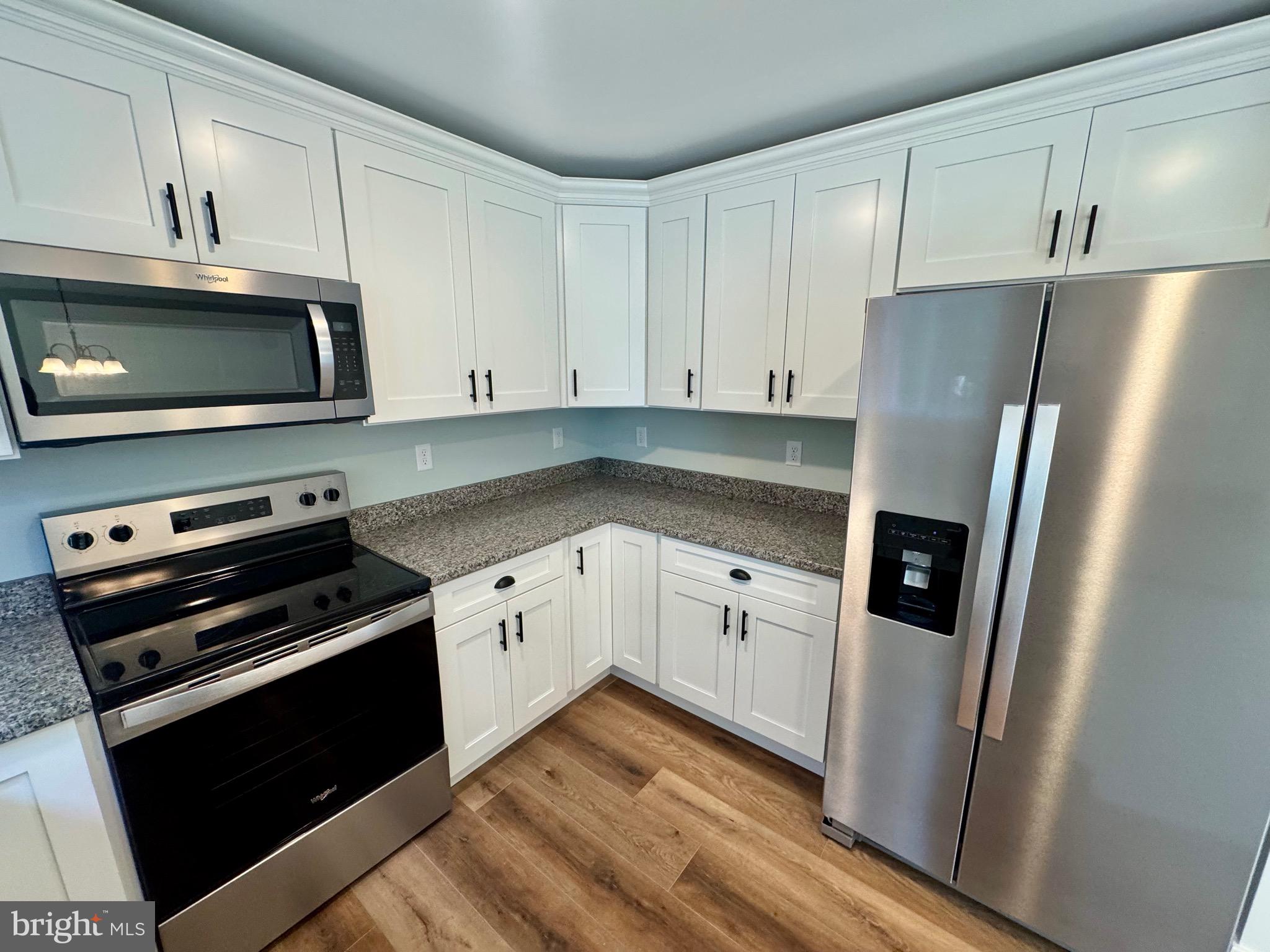 222 Long Point Road Stevensville, MD 21666 - Photo 11 of 44 a kitchen with granite countertop a refrigerator stove and white cabinets