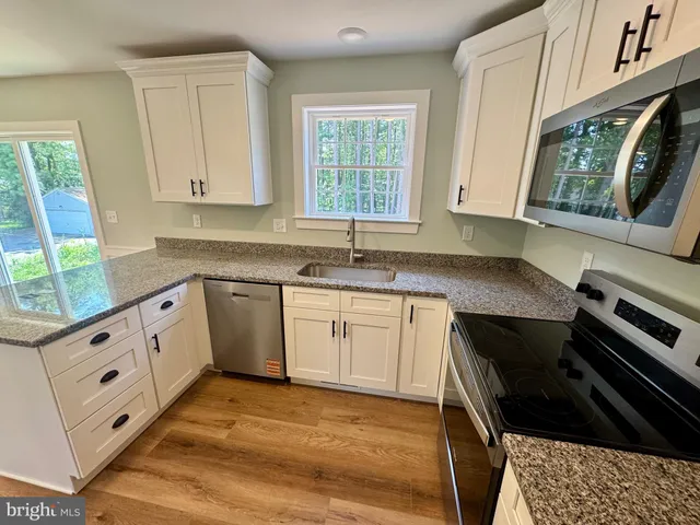 a kitchen with granite countertop stainless steel appliances a counter space and cabinets