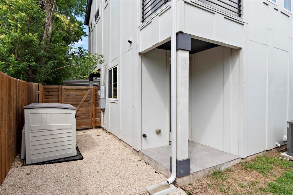 911 Stobaugh Street, Unit 2 Austin, TX 78757 - Photo 25 of 26 White siding exterior with a covered entry, gravel landscaping, and a wood privacy fence