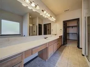 a spacious en suite bathroom with a granite countertop sink and a mirror