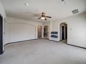 an empty room with chandelier fan and windows