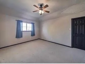 an empty room with a chandelier fan and windows