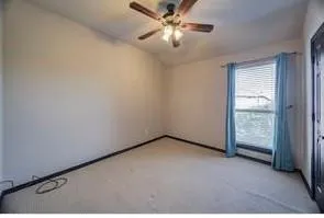 an empty room with a ceiling fan and window
