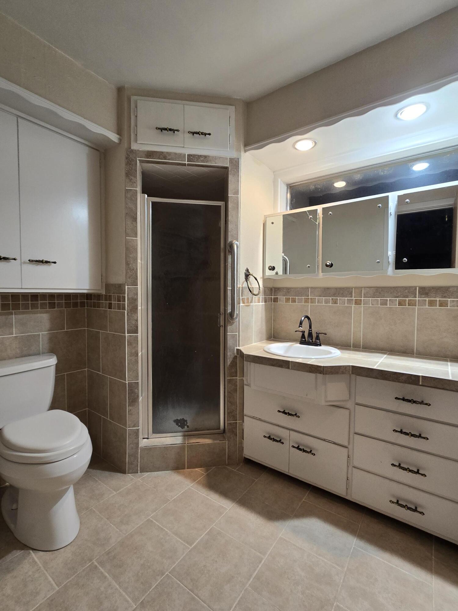 2229 South 6th Street Lamesa, TX 79331 - Photo 13 of 27 a bathroom with a sink a toilet a mirror and shower
