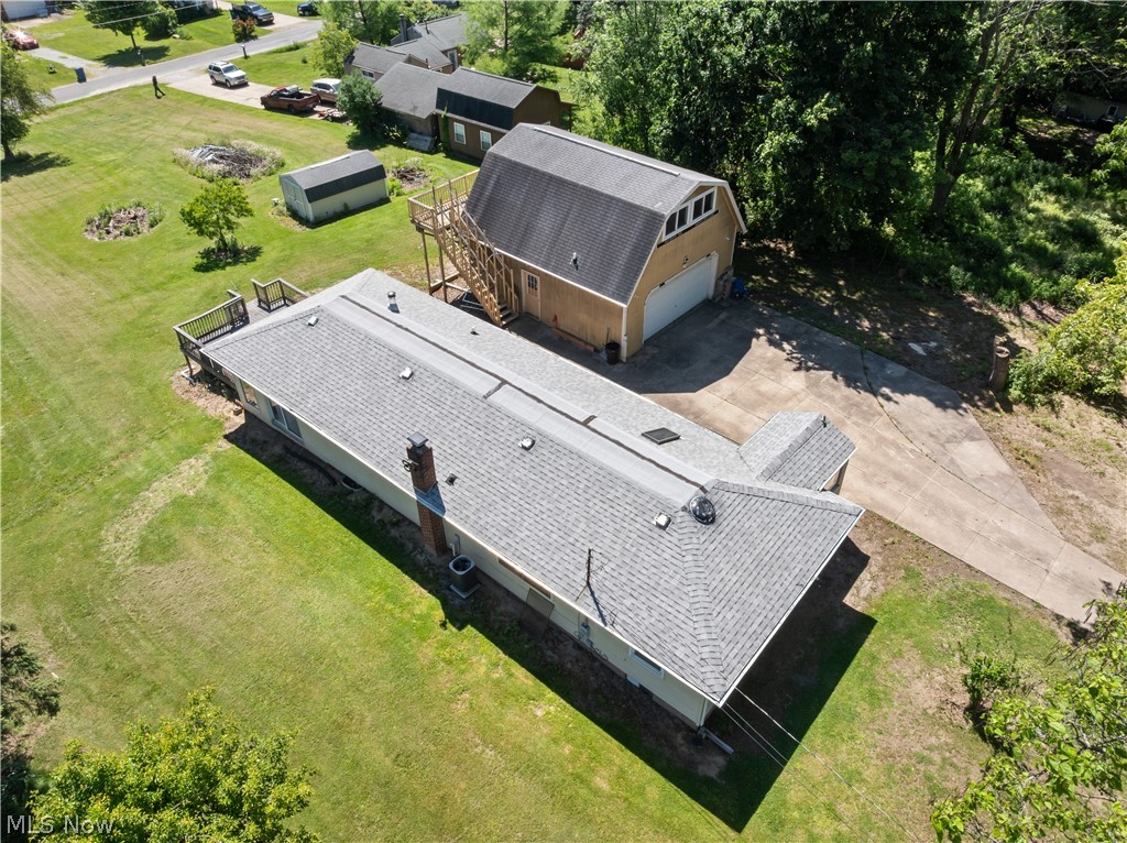409 Edith Avenue Akron, OH 44312 - Photo 6 of 45 Expansive property featuring a residence with a gray shingle roof, a detached two-story garage with a white overhead door, a concrete driveway, a wood deck, and a separate storage shed