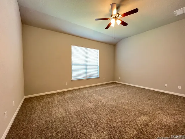 an empty room with windows and chandelier fan