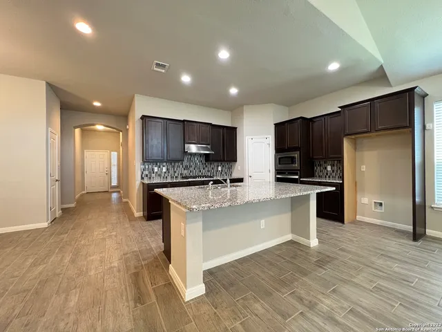 a large kitchen with stainless steel appliances kitchen island a large counter top and a refrigerator