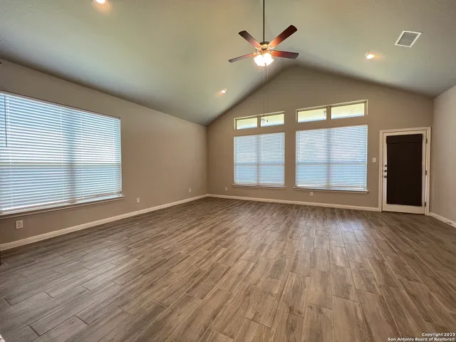 an empty room with wooden floor and windows