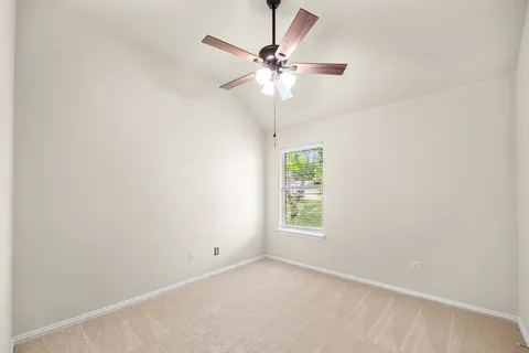 an empty room with a window and a fan