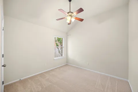 an empty room with window and ceiling fan