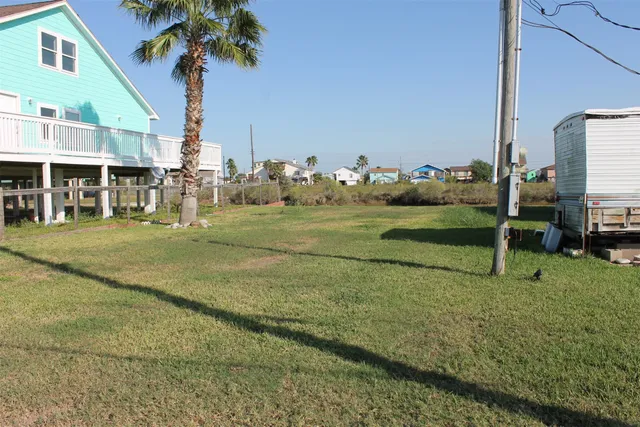 a view of a white house in a big yard with a palm trees