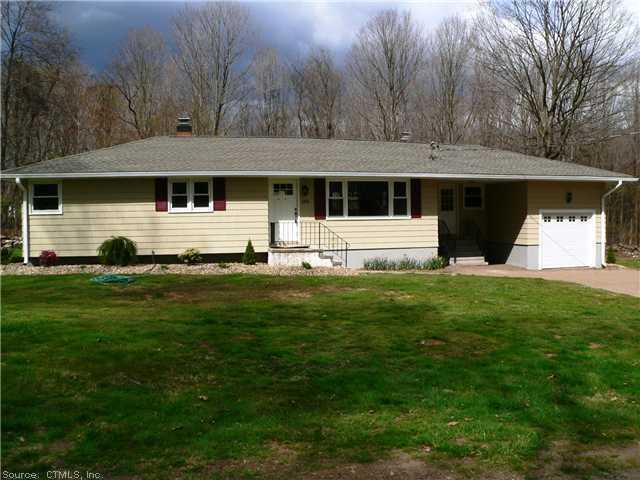 a front view of house with yard and trees in background
