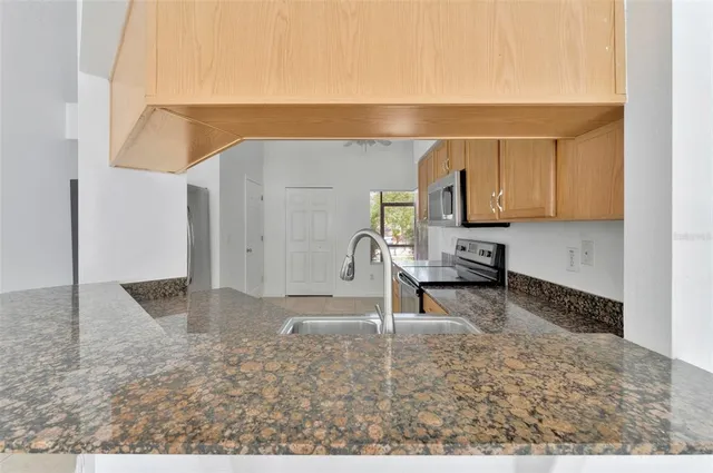 a kitchen with granite countertop a stove a sink and a microwave