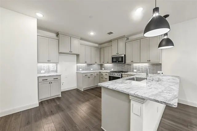 a kitchen with granite countertop a sink stainless steel appliances and cabinets