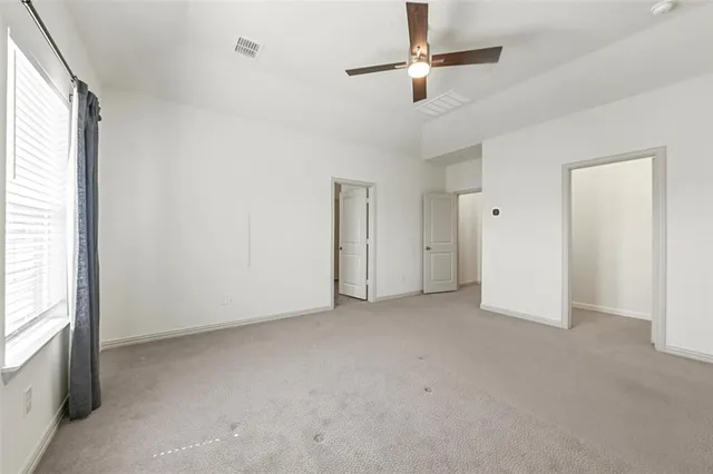 an empty room with ceiling fan and window