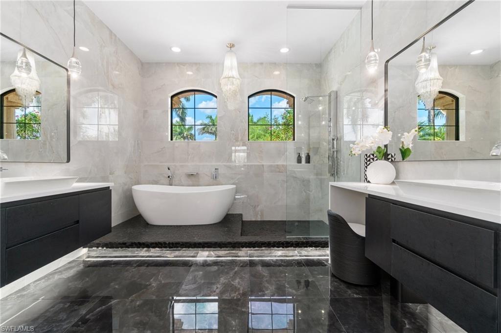 3440 Runaway Lane Naples, FL 34114 - Photo 17 of 42 Bathroom featuring marble tiled flooring, a stall shower, two vanities, a soaking tub, and tile walls