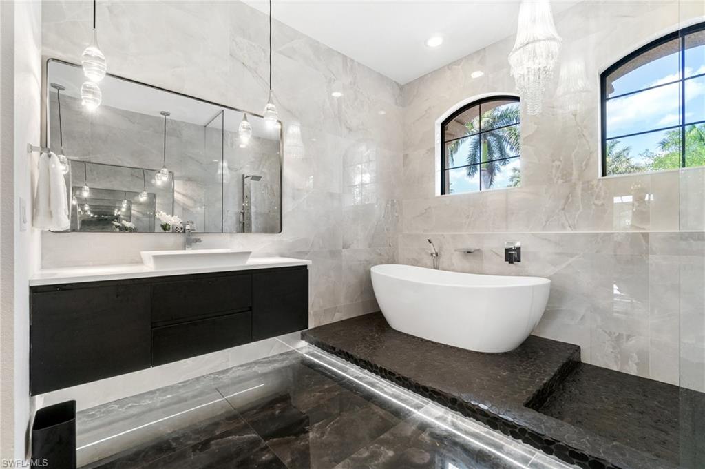 3440 Runaway Lane Naples, FL 34114 - Photo 19 of 42 Bathroom with marble tiled floors, a freestanding bath, tile walls, vanity, and walk in shower