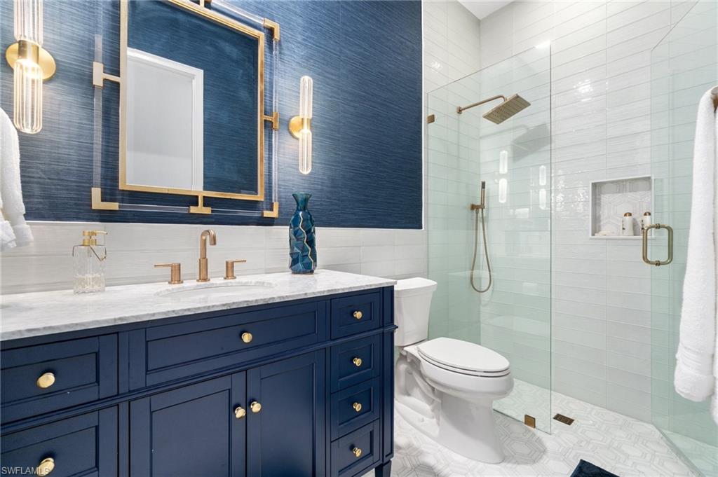 3440 Runaway Lane Naples, FL 34114 - Photo 22 of 42 Full bath with tile walls, vanity, a tile shower, tile patterned flooring, and wainscoting
