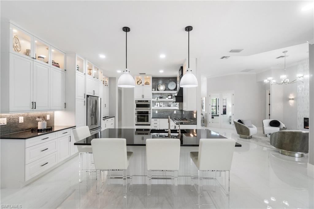 3440 Runaway Lane Naples, FL 34114 - Photo 9 of 42 Kitchen featuring appliances with stainless steel finishes, decorative backsplash, dark countertops, a kitchen bar, and recessed lighting