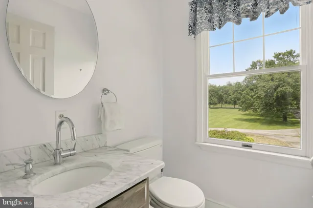 a bathroom with a granite countertop sink a toilet and a mirror